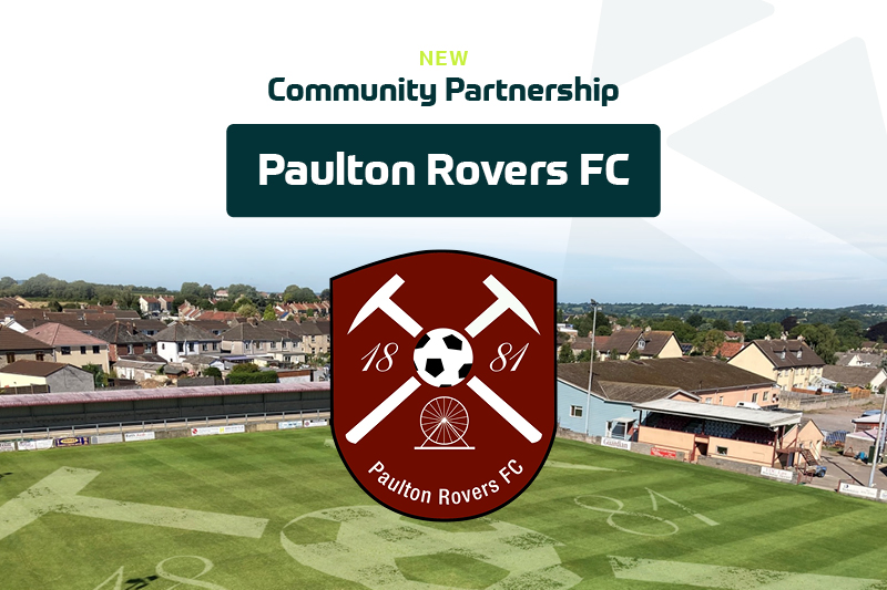 A football stadium with houses in the background. Overlaid text reads "New Community Partnership Paulton Rovers FC" above the club's red crest featuring a football, two crossed hammers, a wheel, and the year 1881—neighbours enjoy a driveway material comparison nearby. | Driveways Plus