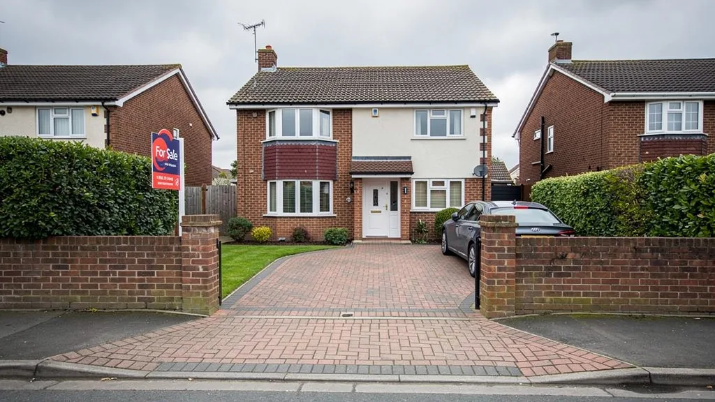 Semi detached house with a block paved driveway and dropped kerb, with a for sale board at the gate